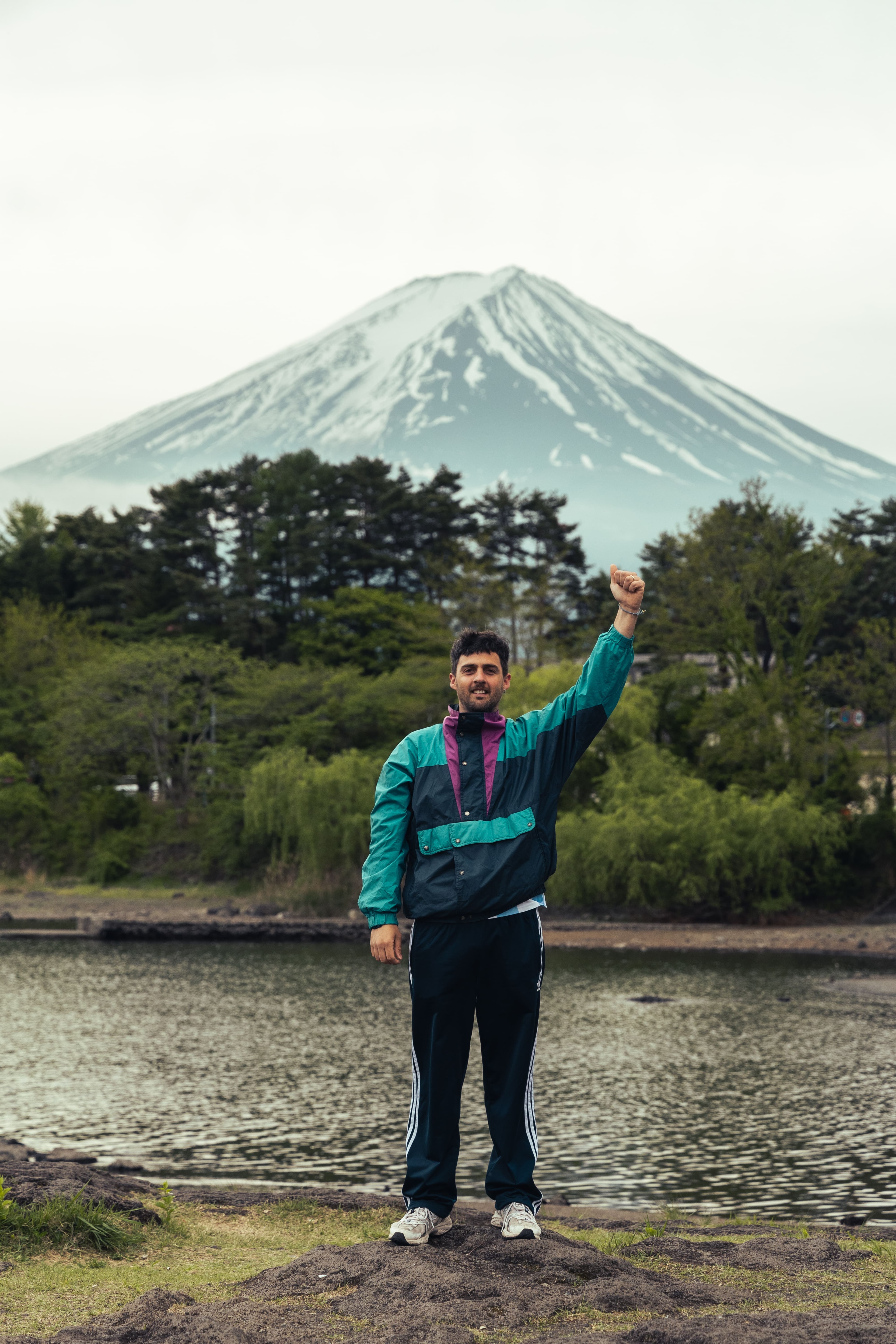 Pato Turri standing with one arm raised, in front of a lake and a snow-capped mountain